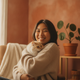Candid portrait of a smiling young adult with East Asian features, suggesting a happy pet parent, against a soft, warm backgr
