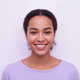 Headshot of a smiling young woman with diverse features, wearing a lavender top, against a bright white background with a hin